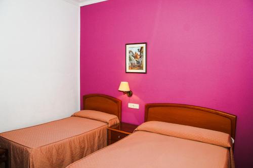 马德里努曼西亚旅馆的一间设有两张床和粉红色墙壁的客房
