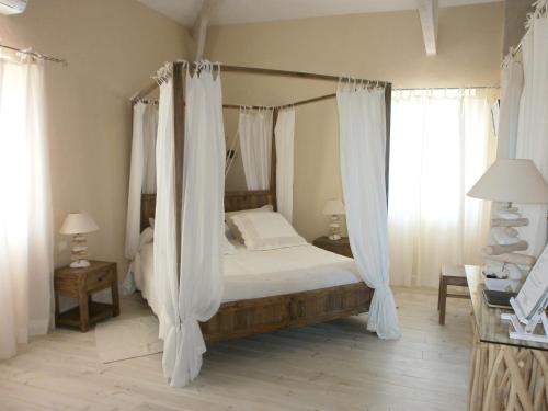Pailloles好葡萄园住宿加早餐酒店的卧室配有带白色窗帘的天蓬床
