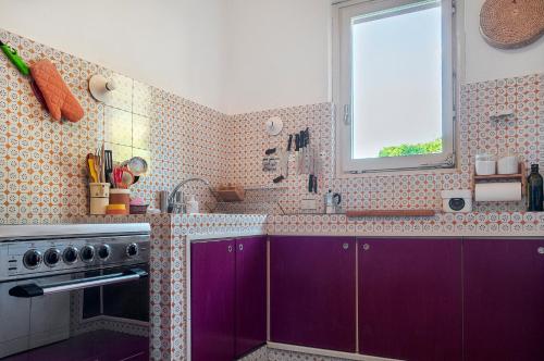 费拉约港Il Grifo - Cozy house, wonderful view的厨房配有紫色橱柜和窗户