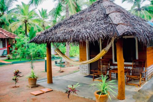 坦加拉Star Light Cabanas & Restaurant的小屋设有吊床和椅子,并种植了棕榈树