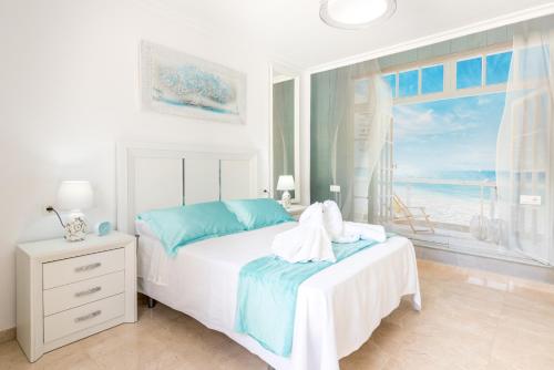 赛阿隆加Villa Felicidad destino romántico的一间白色的卧室,配有一张享有海景的床