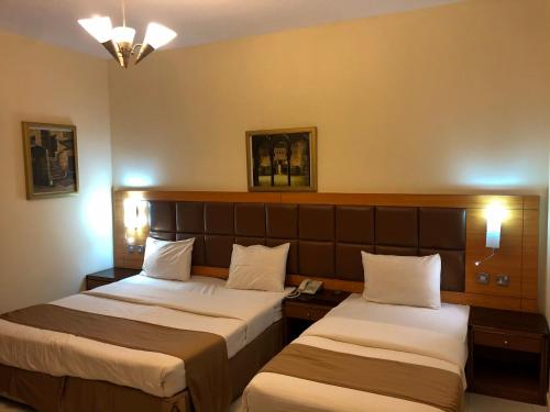 迪拜New Royal Mark Hotel Apartments的酒店客房设有两张床和两盏灯。