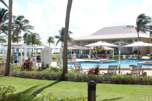 乔治敦The Grand Caymanian Resort的一个带椅子和遮阳伞的游泳池的度假酒店