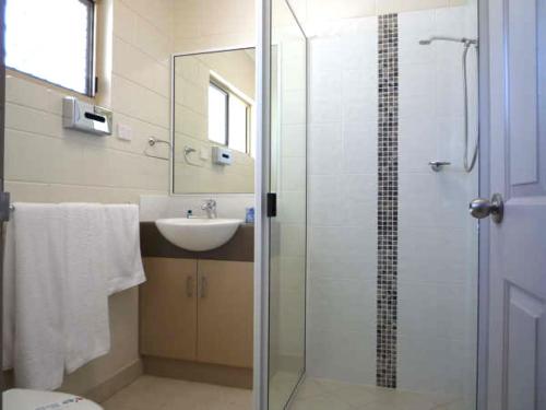 CollinsvilleCollinsville Motel的一间带玻璃淋浴和水槽的浴室