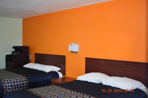 罗斯威尔Belmont Motel的酒店客房设有两张床和橙色的墙壁。