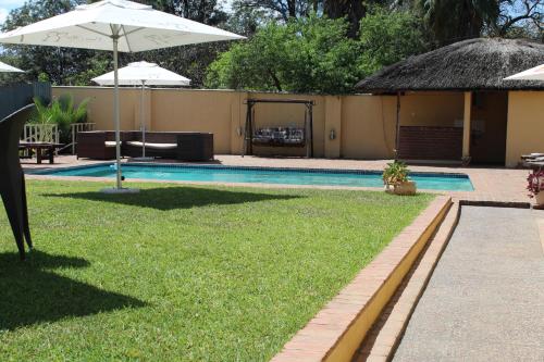 布兰太尔Casa Mia Lodge & Restaurant的一个带遮阳伞和草地的游泳池