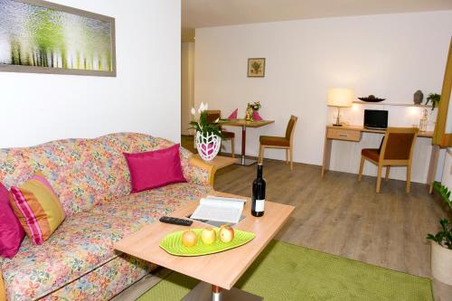 LenzingFerienwohnungen - Boarding Wohnungen Sonnenhof的客厅配有沙发和一张桌子及一瓶葡萄酒