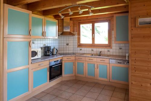 莱热Chalet Le Lapye的一间设有蓝色橱柜和窗户的大厨房