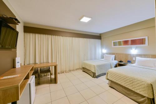 戈亚尼亚Plaza Inn Augustus的酒店客房配有两张床和一张书桌