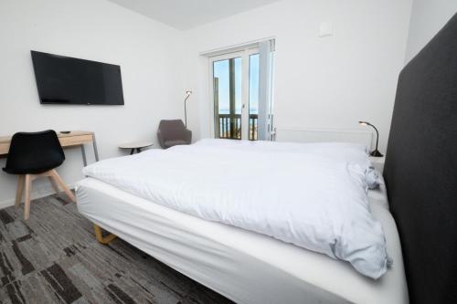 伊卢利萨特艾斯菲尔得公寓酒店的卧室配有白色的床、书桌和电视。
