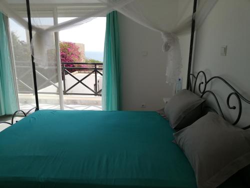 土巴迪亚劳Villa Roka - Toubab Dialaw的一间卧室设有一张绿色的床和一个窗户。