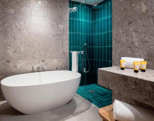 科尔蒂纳丹佩佐法洛里亚山Spa度假酒店的浴室设有浴缸和绿色瓷砖淋浴。