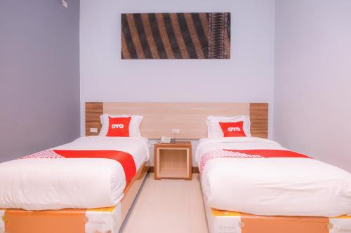 班达亚齐Super OYO Capital O 1630 Hotel Syariah Ring Road的一间设有两张红色和白色床单的房间