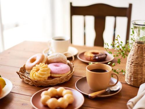 名古屋Sotetsu Fresa Inn Nagoya Sakuradoriguchi的一张木桌,上面放着甜甜圈和咖啡杯