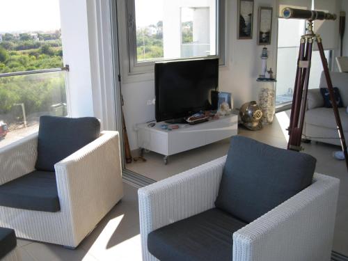 普罗塔拉斯三叉戟海滩公寓的客厅配有2把椅子和平面电视