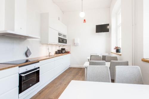卡尔斯克鲁纳Kronohäktet的厨房配有白色橱柜和灰色椅子