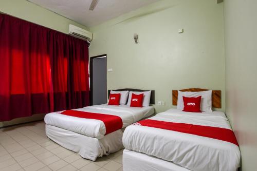 太平OYO 89549 Casavilla Hotel (city Centre) Taiping的两张位于酒店客房的床铺,配有红色枕头