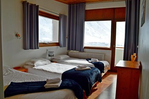 蒂涅Le Terril Blanc的酒店客房设有三张床和窗户。