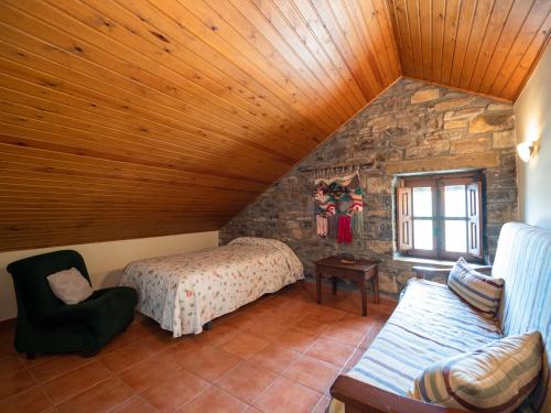 El Pueyo de Araguás卡萨日冕乡村民宿的阁楼卧室设有一张床和石墙
