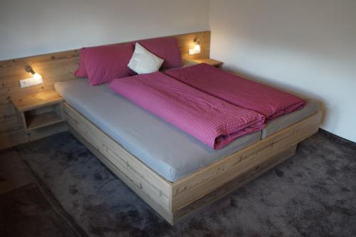 托巴迪尔Pferdehof Bachegg的一间卧室配有一张带粉色床单的木床