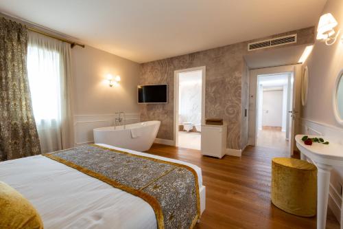 维托里奥·威尼托Relais Althea Azienda Agrituristica的一间卧室配有一张床、一个浴缸和一台电视。