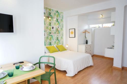 马拉加Alemania & SOHO by ELE Apartments的白色卧室配有一张床和一张桌子及一张桌子