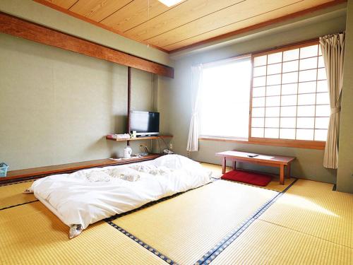 Saitobusiness ryokan haniwa的一间卧室设有一张床、一个窗口和一张桌子