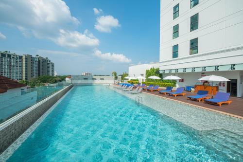 清迈The Empress Premier Chiang Mai - SHA Extra Plus的一座带蓝色椅子的游泳池和一座建筑