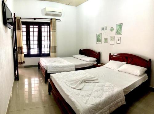 顺化安轩旅馆的一间卧室设有两张床,其中设有窗户。