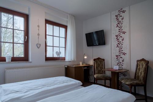 吕本Hotel & Restaurant Lindengarten的一间卧室配有一张床、两把椅子和一张书桌