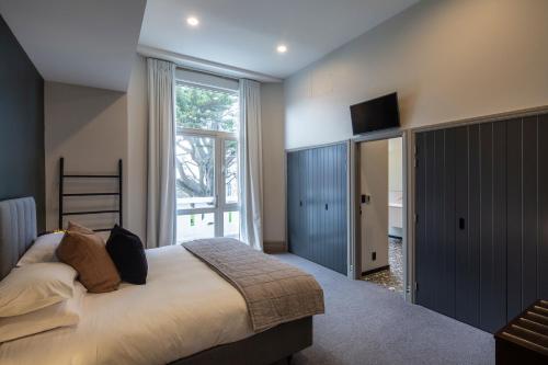 但尼丁The Burlington Luxury Octagon Apartment的一间卧室设有一张大床和一个大窗户