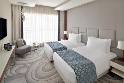 迪拜Mövenpick Hotel Apartments Downtown Dubai的酒店客房设有两张床和电视。