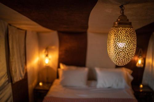 姆哈米德Bivouac de luxe Mhamid的一间卧室配有一张床和一个吊灯