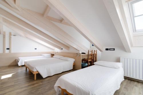 圣米凯莱亚拉迪杰阿菲塔卡米莉拉费拉塔旅馆的阁楼卧室设有两张床和窗户。