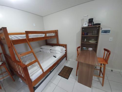因比图巴Kitnet Praia da Vila Imbituba的一间卧室配有一张双层床、一张桌子和一张书桌。