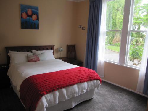 HalcombeThyme Out Estate的一间卧室配有一张带红色毯子的床和窗户。
