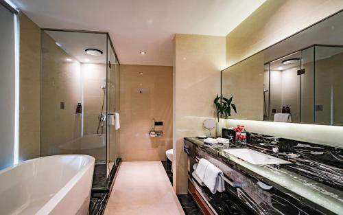 常州常州华美达国际大酒店的浴室配有2个盥洗盆、浴缸和淋浴。