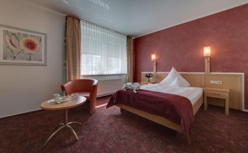 兰施图尔Hotel Merkur的酒店客房,配有床、桌子和椅子