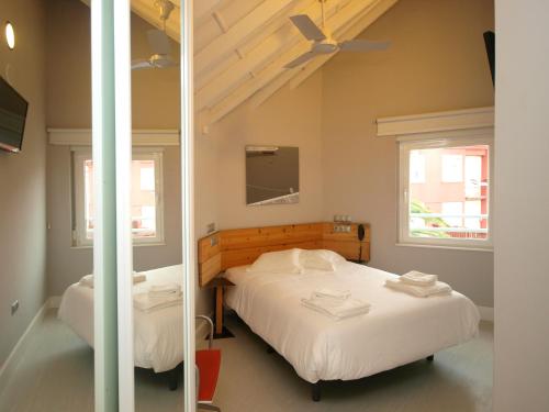 桑坦德桑坦德霍斯蒂亚酒店的一间卧室设有两张床,墙上配有电视。