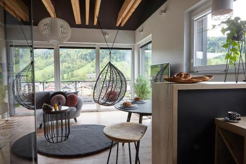 什切尔克Apartament Balance z prywatną sauną的客厅配有秋千椅和桌子