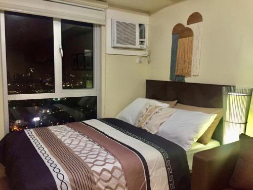 宿务Cozy studio in Cebu IT Park的一间卧室设有一张床和一个享有城市美景的窗户