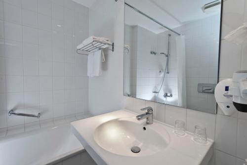 波茨坦波茨坦温德姆花园酒店的白色的浴室设有水槽和镜子