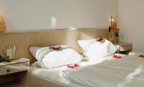 贝尔恩里德Hotel Winterl的一张白色的床,枕头上放着红色的鲜花