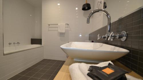 古尔本The Astor Suites的浴室配有盥洗盆和浴缸。