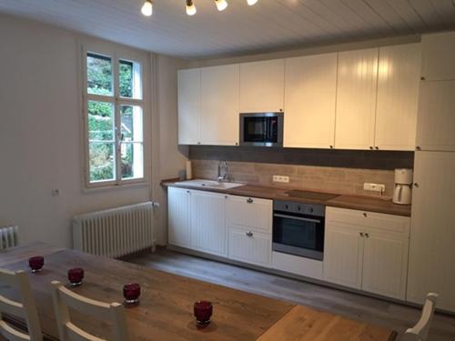 蒙绍Maison Riviére的厨房配有白色橱柜和木桌