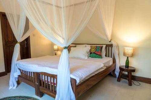 恩德培Muti Entebbe的一间卧室配有一张带天蓬的床