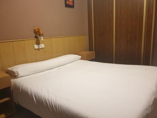 马德里休憩旅馆的卧室配有白色床,墙上挂着泰迪熊