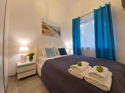 尤斯托尼莫斯基DWIE SOSNY-Apartament na wydmie - 365PAM的一间卧室配有蓝色窗帘和一张带毛巾的床