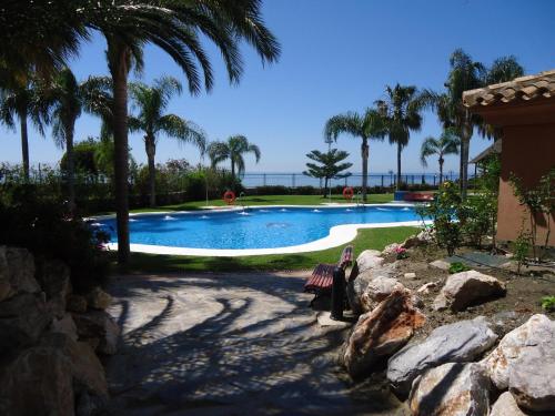 阿尔姆尼卡Getaway Apartment的一个带棕榈树和长凳的游泳池