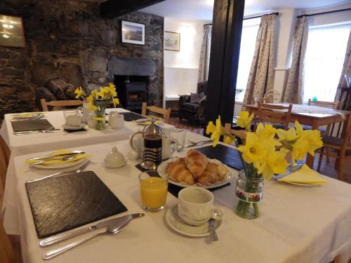 多尔盖罗Aber Cottage B&B的一张桌子,上面放着一盘羊角面包和黄色的鲜花